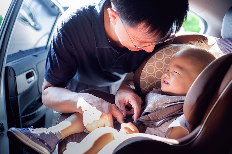 Insurance Quote - Close Up View of a Cheerful Father Buckling Up His Baby in the Car Seat